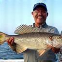 James Tan holding a large, freshly caught Grouper fish with a wide smile